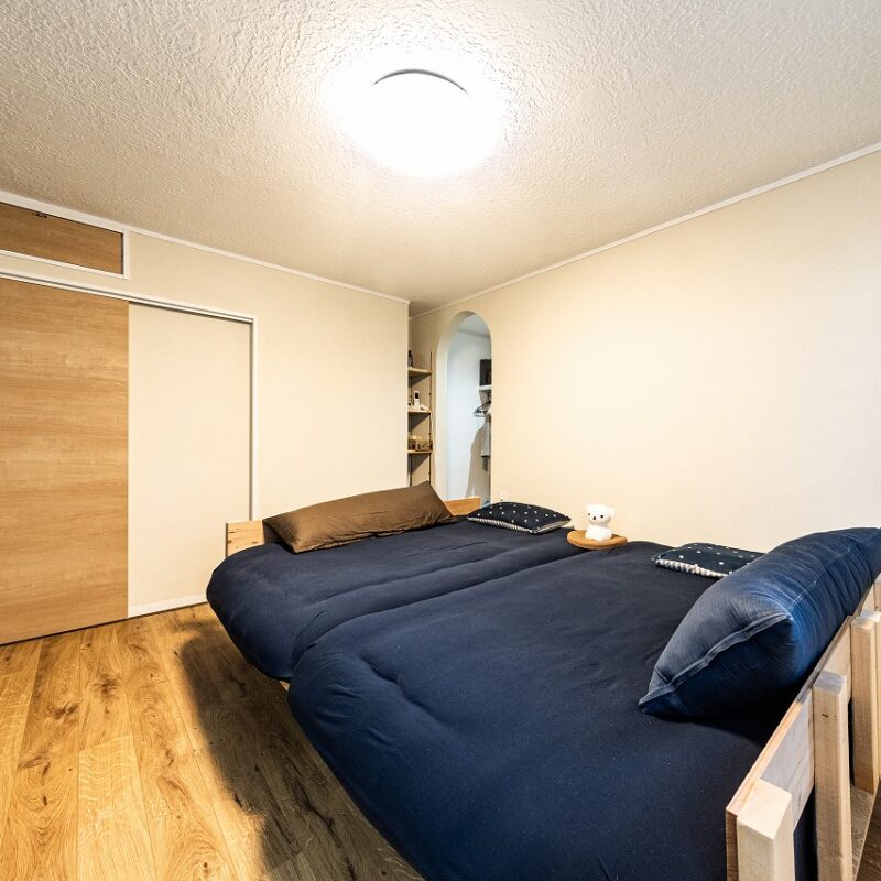 主寝室はプライベートな空間だからと、遊び心を加えて壁の一面を青色に。クローゼットは使いやすさを重視して扉を付けず、アーチ型の入口にした。