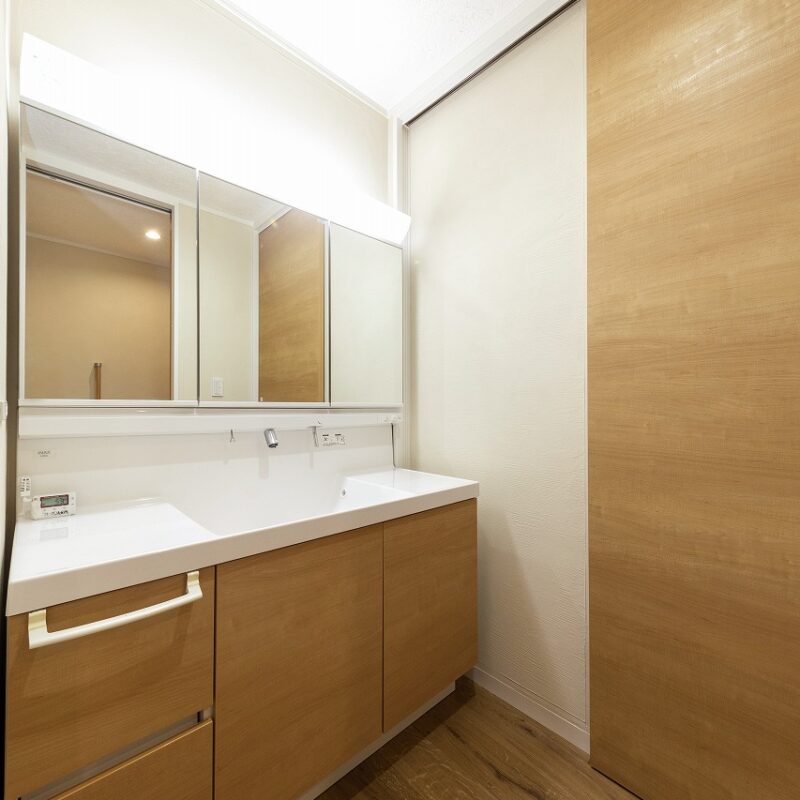 洗面室の洗面台は2人並んで利用できる鏡もワイドなカウンタータイプ。脱衣室に隣接しているが、誰かが入浴している時でも利用できるように間にドアを設けた。