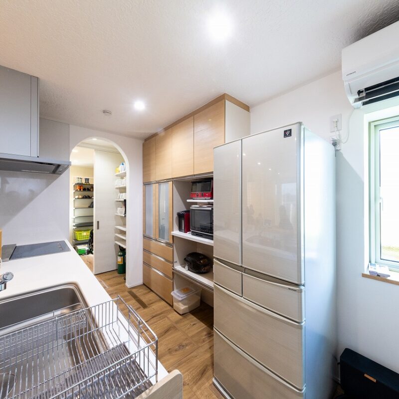 対面キッチンの高さは奥様の使い勝手に合わせて、やや高めの90㎝。背面収納とともに建具と同系色の明るい木目調でそろえた。夏の日中はキッチン上部のエアコン1台で家全体を快適な温度に保つ。