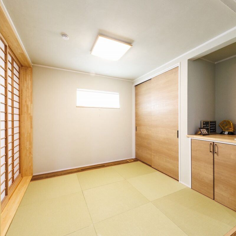 普段はお子様の遊び場に、来客時は応接室として活用している和室は、淡いベージュの壁に琉球畳をあしらった温もりある空間。腰高の収納は上に雛人形や家族写真を置くスペースに。