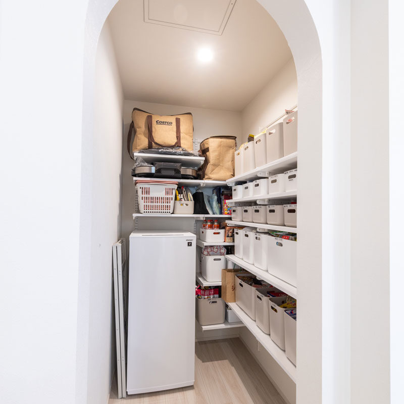 パントリー入口のR形状の下り壁は、奥様がインスタで見つけてぜひ採用したかったものの1つ。圧迫感がなく、空間と空間がほんのり仕切られてる感じが気に入っているそう。冷凍庫を置けること、ホットプレートを取り出しやすいように置けることなど第一に、棚を造り付けで設えてもらっている。