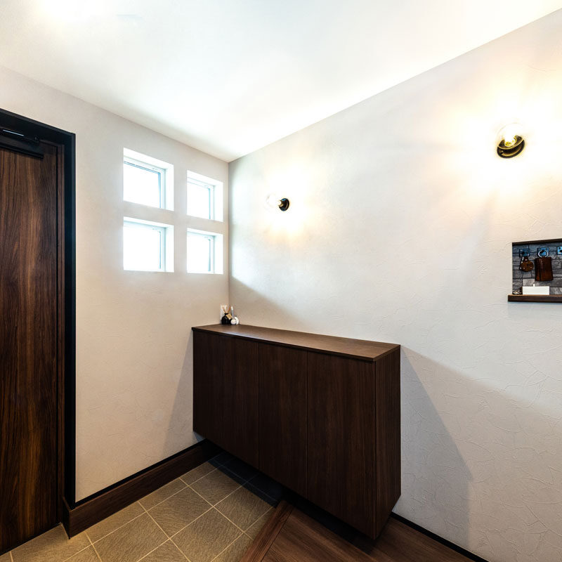 ４つのデザイン窓からの光で明るい玄関。靴箱の右側の壁にニッチ収納も作ってあり、車の鍵類が掛けられるようになっていて、お出かけ対策は万全。