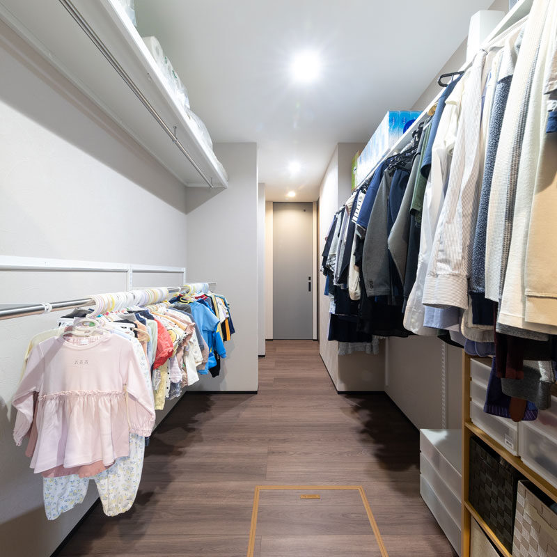 Ｍ様邸２つ目の回遊動線は、キッチンを中心とする大きな動線。キッチン背面側の廊下の両側には、長～いハンガーポールが設けられていて、家族全員分の衣類がずらりと並ぶファミリークローゼット。「廊下とクローゼットが兼用できたら効率的！と閃いた間取りです！」と奥様。ドアをつけず、通り抜けができる収納は便利なこと、この上なしだそう。