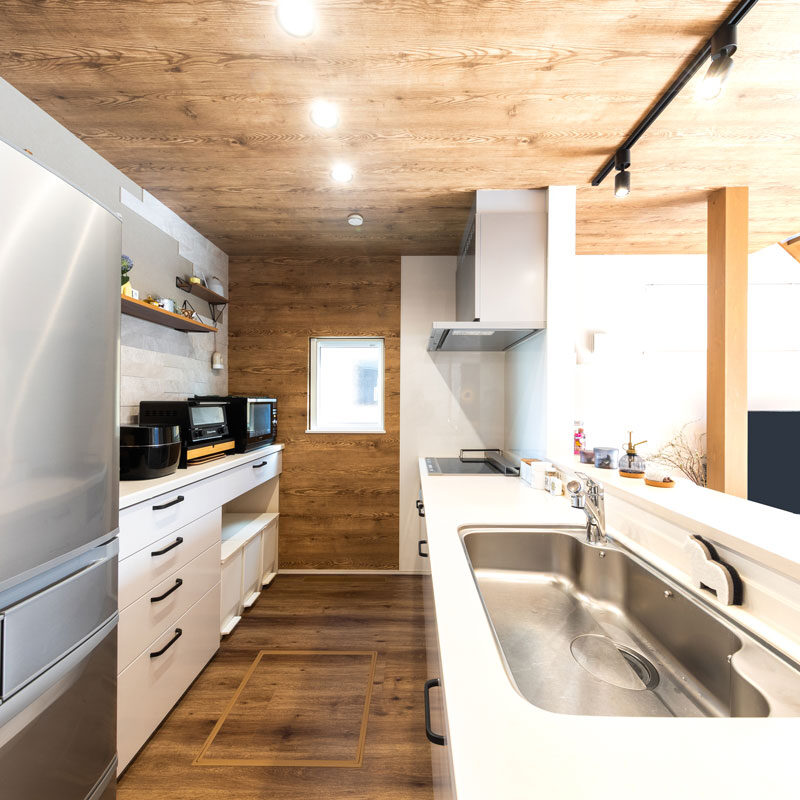 ゆとりのあるキッチンになり、ご長男と一緒に料理をする機会が増えたという。「IHで火を使わないので安心感もあります」（奥様）。突き当たりの壁は当初、他の面と同じ白の漆喰クロスを使う予定だったが、汚れの落ちにくさを考慮して天井の木目クロスを延長させた。