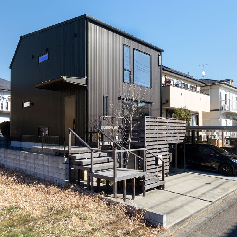 もともとの地盤の高さを生かして高基礎に。ウッドデッキ下の空間を自転車置き場として利用している。建物の形は総２階。「気密性を損なわないよう、壁紙の継ぎ目が少ないシンプルな形に」（ご主人）