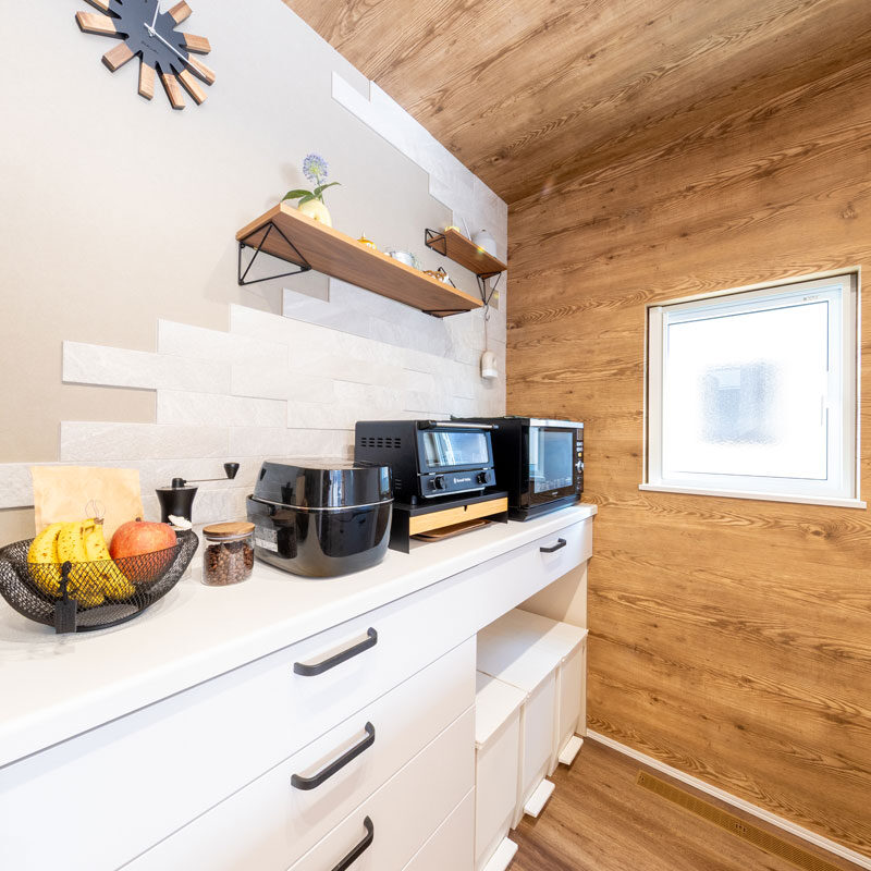 奥様の動線に合わせてキッチン家電を並べ、作業効率をアップ。壁の飾り棚はご夫妻があとづけしたもので、そのまわりを余ったエコカラットであしらった。