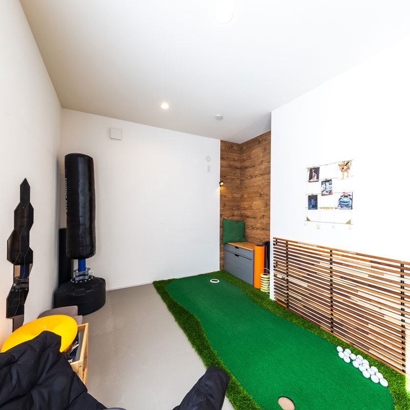 オープンな4.5畳の洋間を父と子のトレーニングルームに。隣室のクローゼットと互い違いになった凹み部分を収納スペースとして活用。ゴルフマットの横にエクステリア用の柵を置き、ライン照明を仕込むなどで飾りになっている。