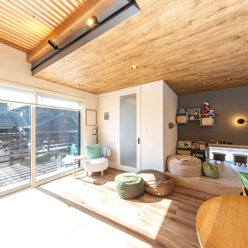 ウッドデッキとつながる大空間。室内の木目と自然につながるよう、ウッドデッキにも本物の木を使い色味を合わせた。普段はスクリーンを下げているが、高基礎のため開けていても外から室内が見えにくく、リラックスできる。